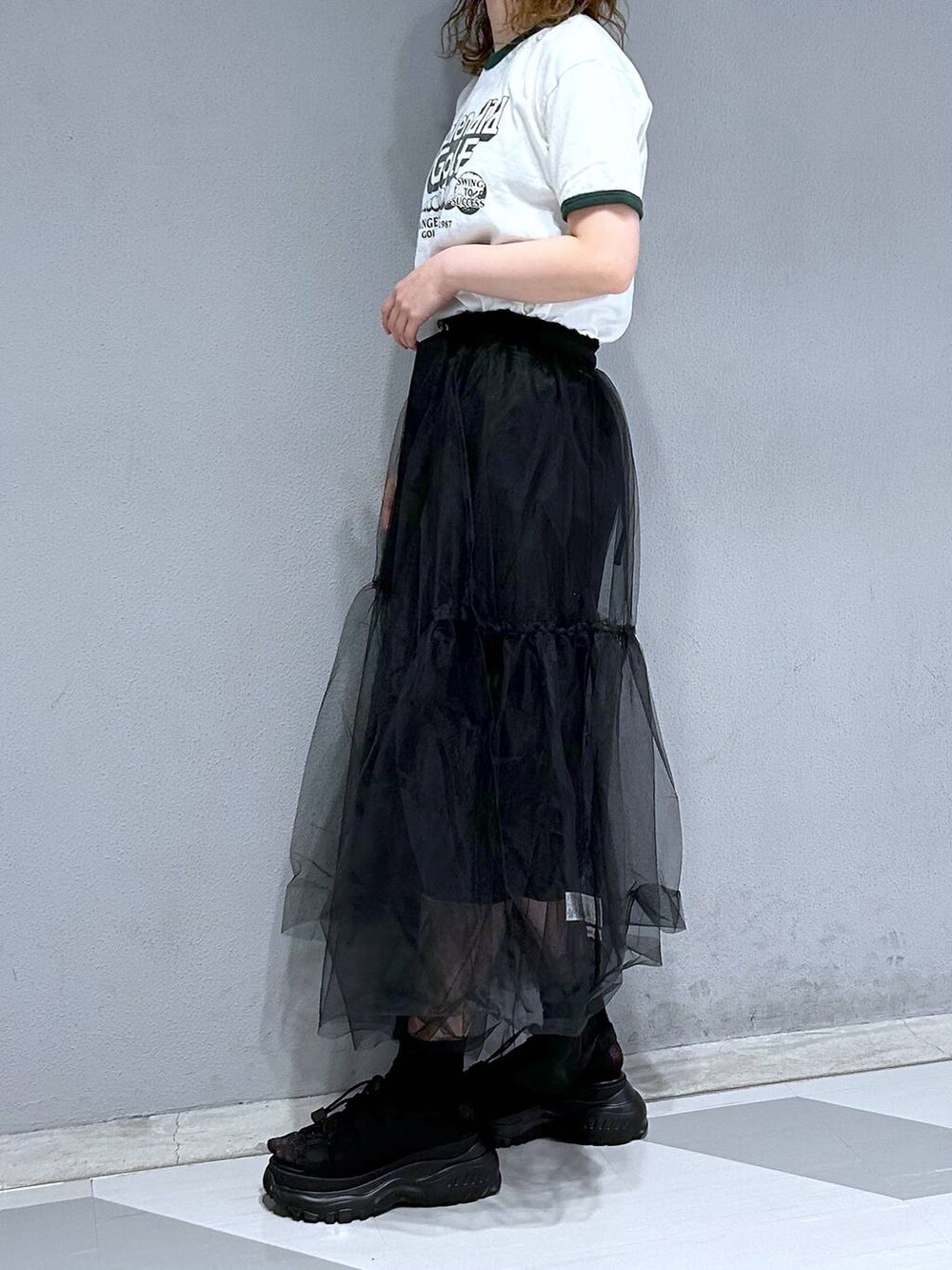 グリーン系のTシャツ/カットソー、ブラック系のスカートを着用したレディースの春コーディネートの3枚目の写真