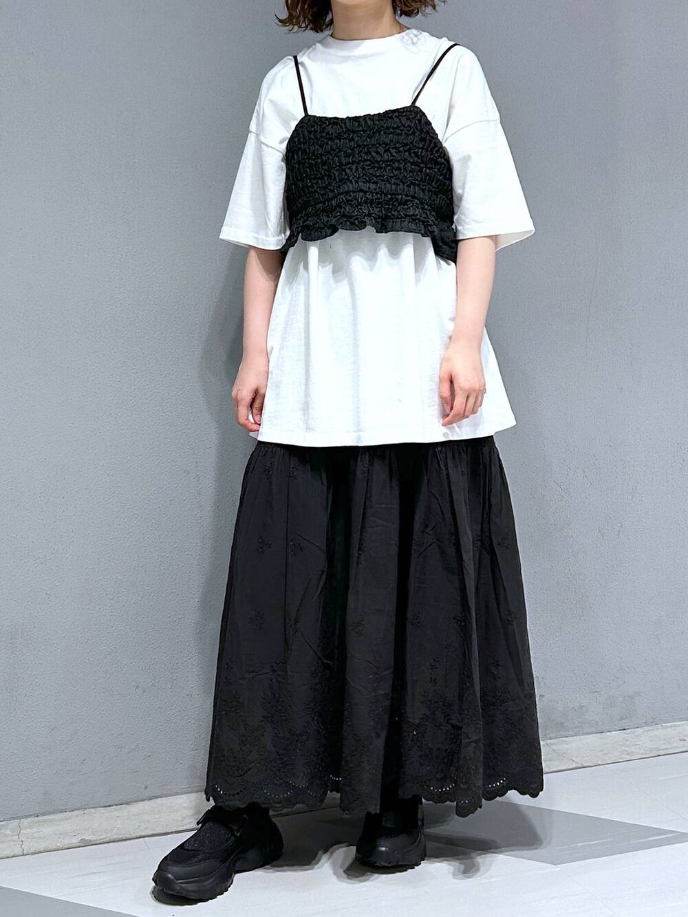 ブラック系のベスト、ホワイト系のTシャツ/カットソー、ブラック系のスカートを着用したレディースの夏コーディネートの3枚目の写真