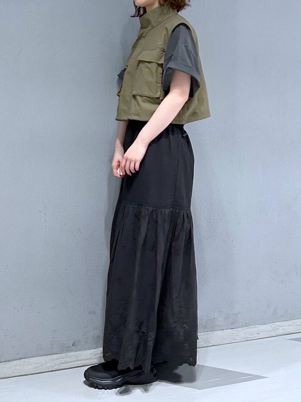 ブラック系のスカート、グリーン系のベスト、ブラック系のTシャツ/カットソーを着用したレディースの夏コーディネートの3枚目の写真