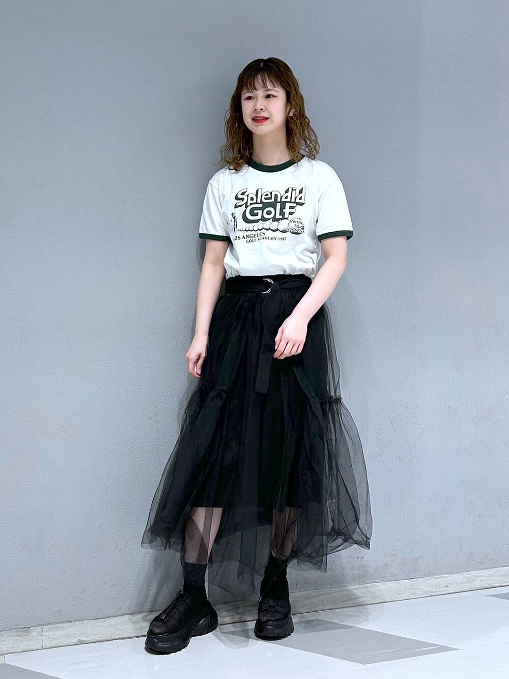 グリーン系のTシャツ/カットソー、ブラック系のスカートを着用したレディースの春コーディネートの4枚目の写真