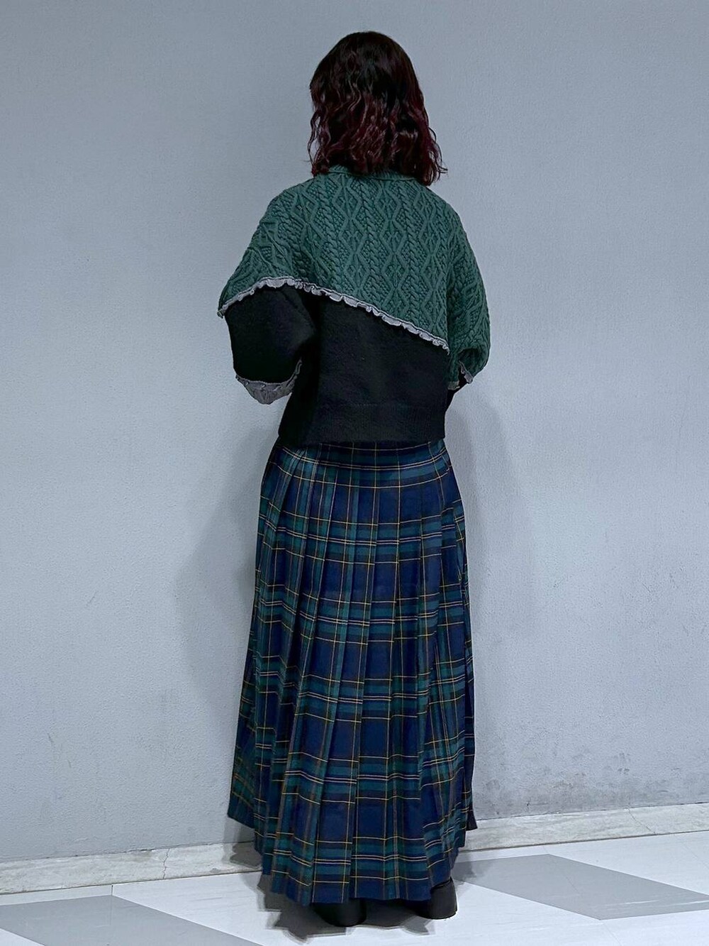 ブラック系のブーツ、グリーン系のスカート、ブラック系のニット/セーターを着用したレディースの秋コーディネートの5枚目の写真