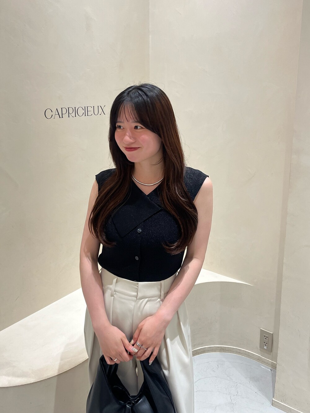 ブラック系のニット/セーター、ホワイト系のその他パンツ、ブラック系のショルダーバッグを着用したレディースの夏コーディネートの2枚目の写真