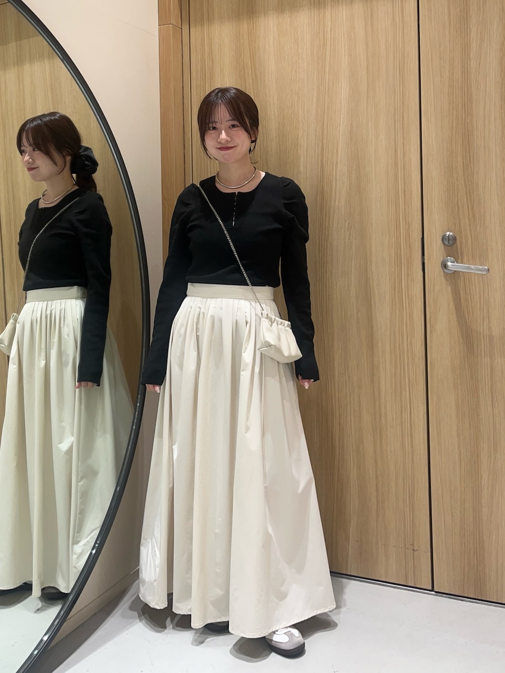 ブラック系のニット/セーター、ホワイト系のスカート、ホワイト系のショルダーバッグを着用したレディースの冬コーディネートの2枚目の写真