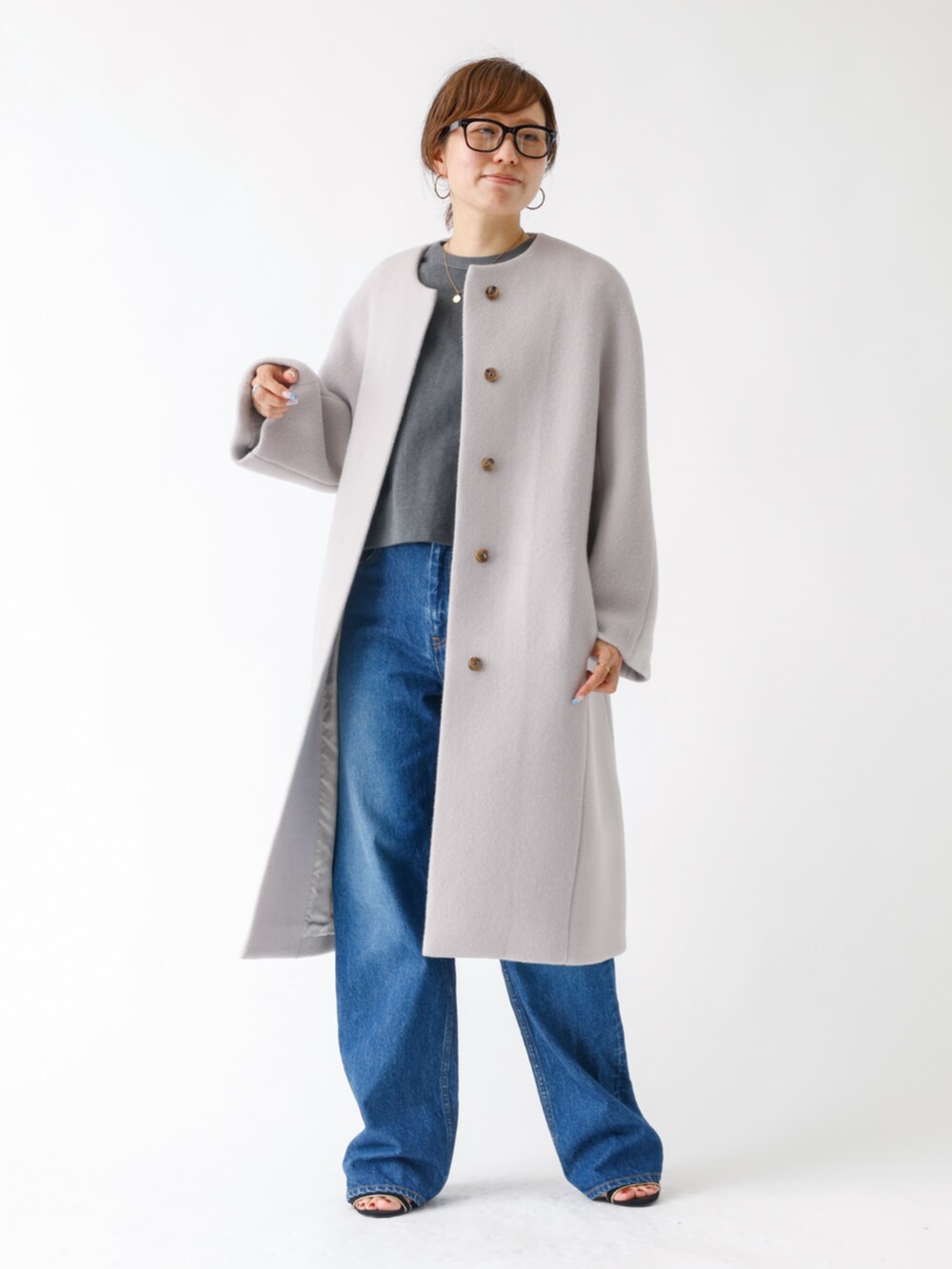 ベージュ系のステンカラーコートを着用したレディースの夏コーディネートの2枚目の写真