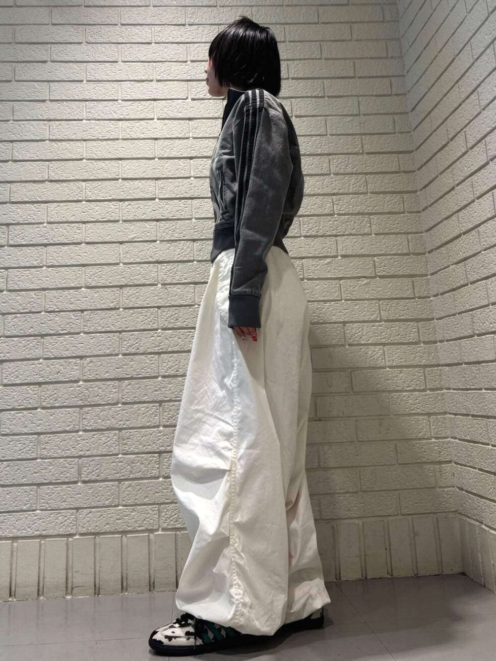 グレー系のデニムジャケット、ブラック系のスニーカーを着用したレディースの夏コーディネートの2枚目の写真