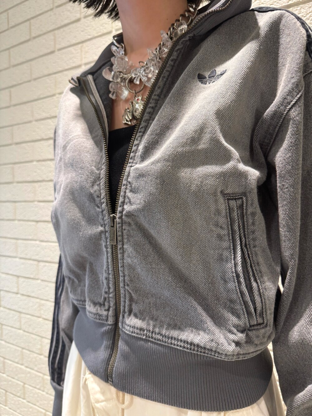 グレー系のデニムジャケット、ブラック系のスニーカーを着用したレディースの夏コーディネートの3枚目の写真