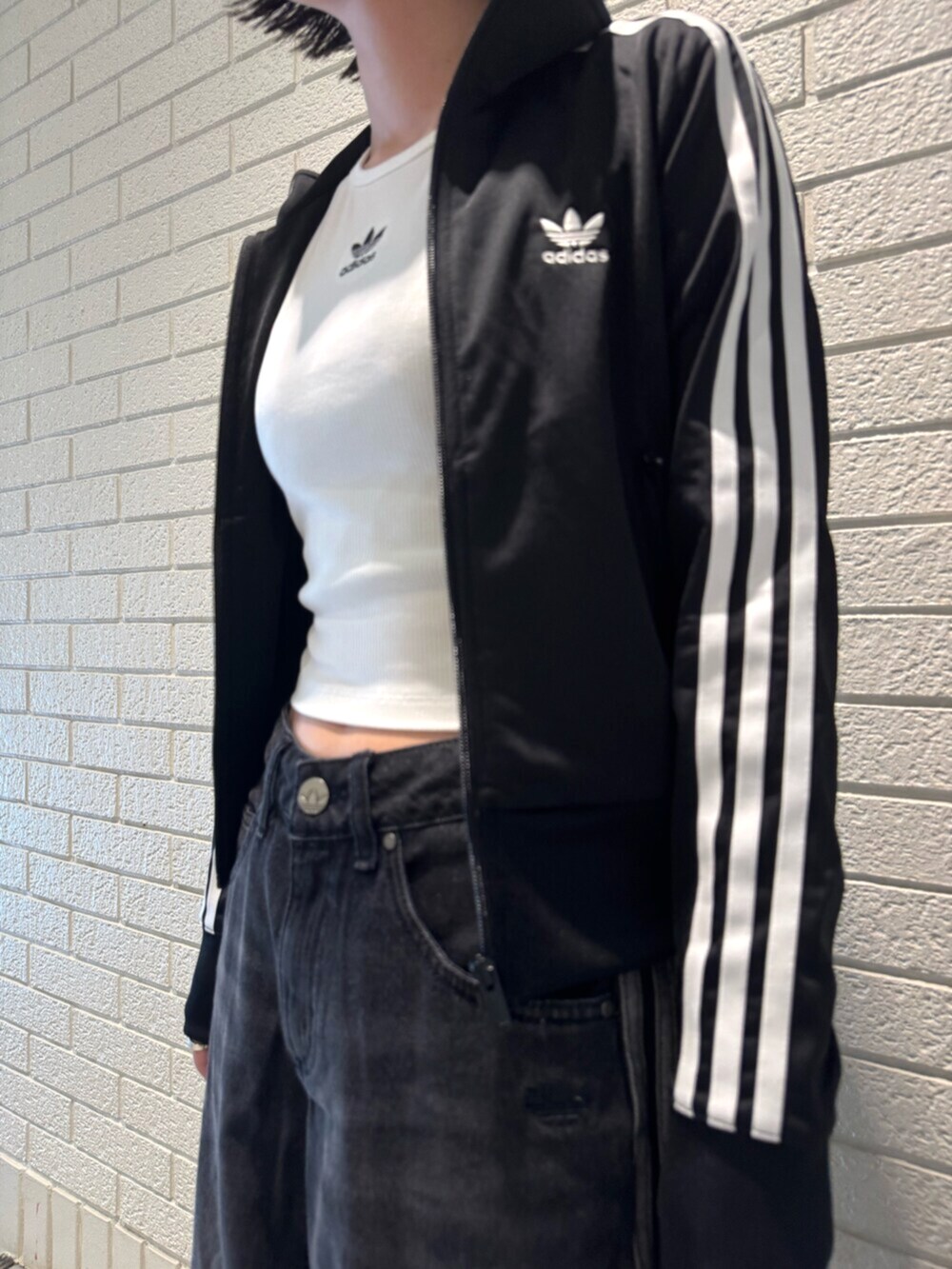 ブラック系のジャージ、ホワイト系のタンクトップ、ブラック系のデニムパンツを着用したレディースの夏コーディネートの3枚目の写真