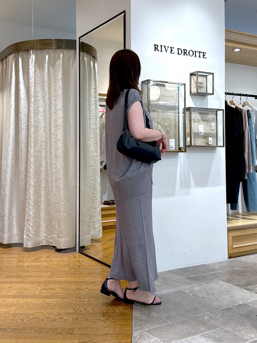 グレー系のニット/セーター、グレー系のスカート、ブラック系のハンドバッグを着用したレディースの夏コーディネートの2枚目の写真