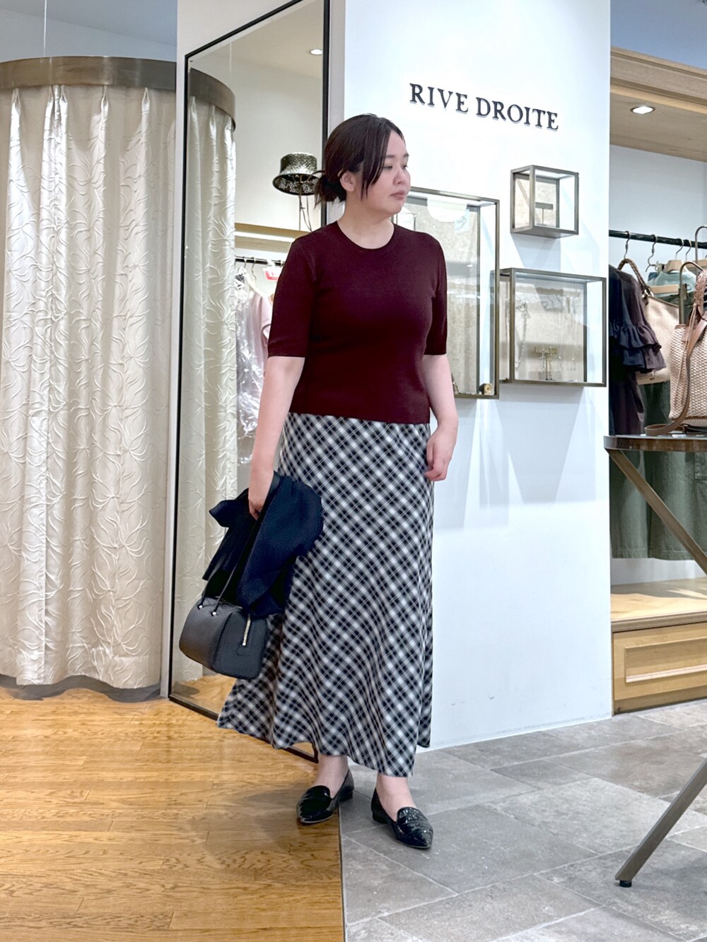 レッド系のニット/セーター、ブラック系のスカート、ブラック系のショルダーバッグを着用したレディースの夏コーディネートの2枚目の写真