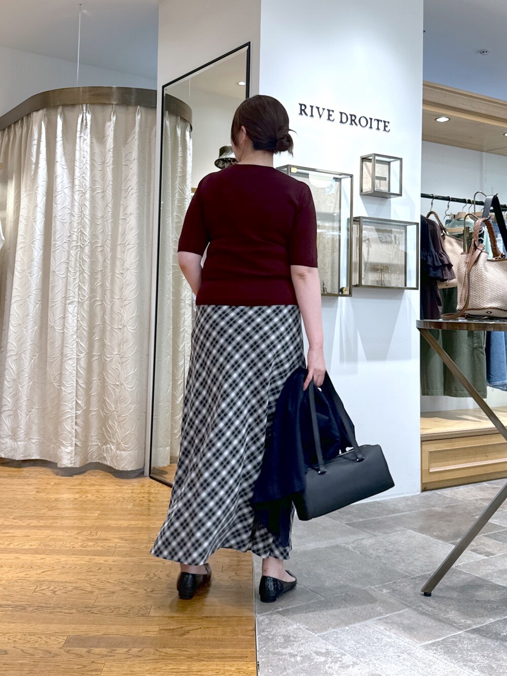 レッド系のニット/セーター、ブラック系のスカート、ブラック系のショルダーバッグを着用したレディースの夏コーディネートの3枚目の写真