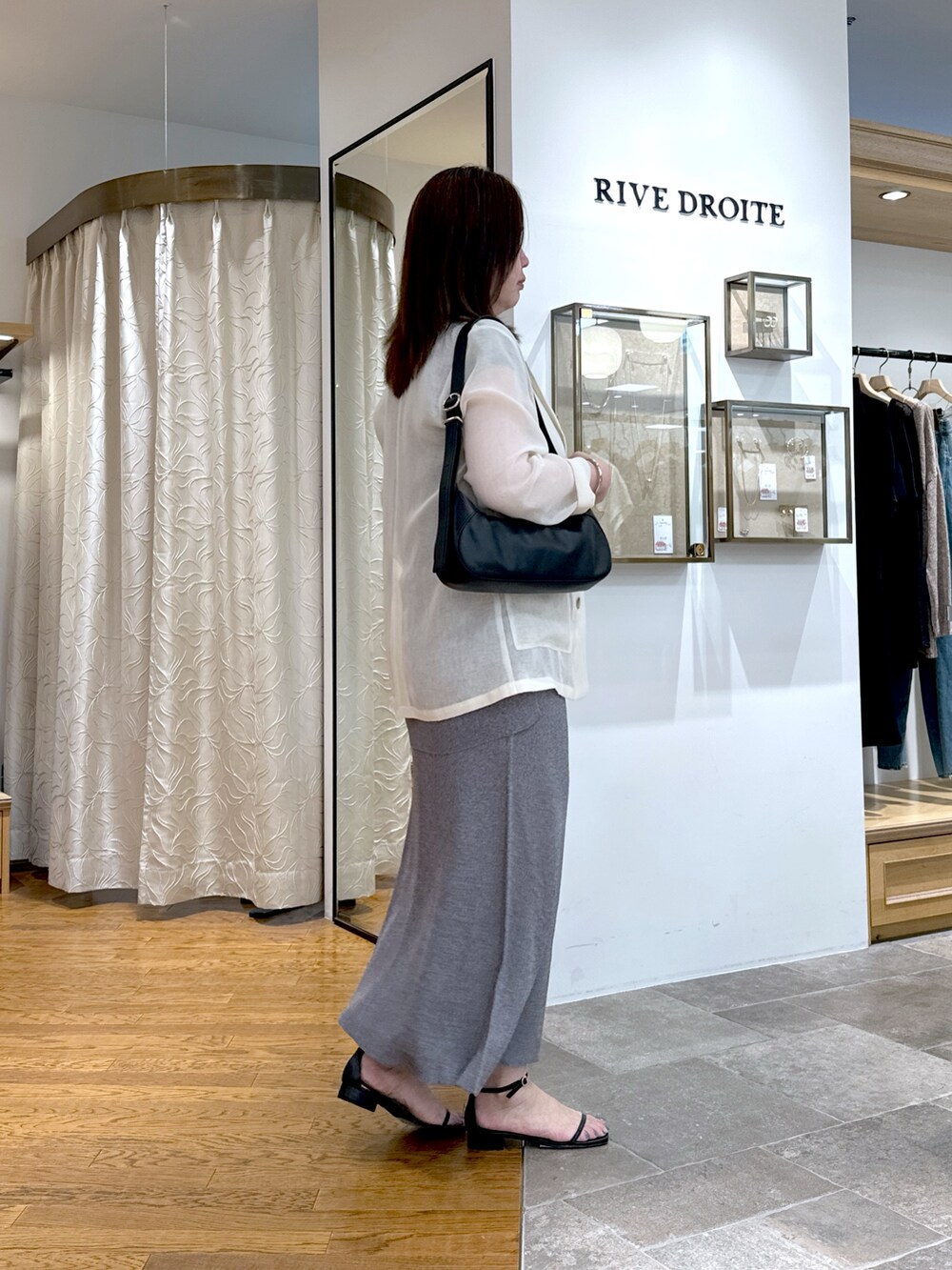 ホワイト系のテーラードジャケット、グレー系のニット/セーター、グレー系のスカートを着用したレディースの夏コーディネートの2枚目の写真