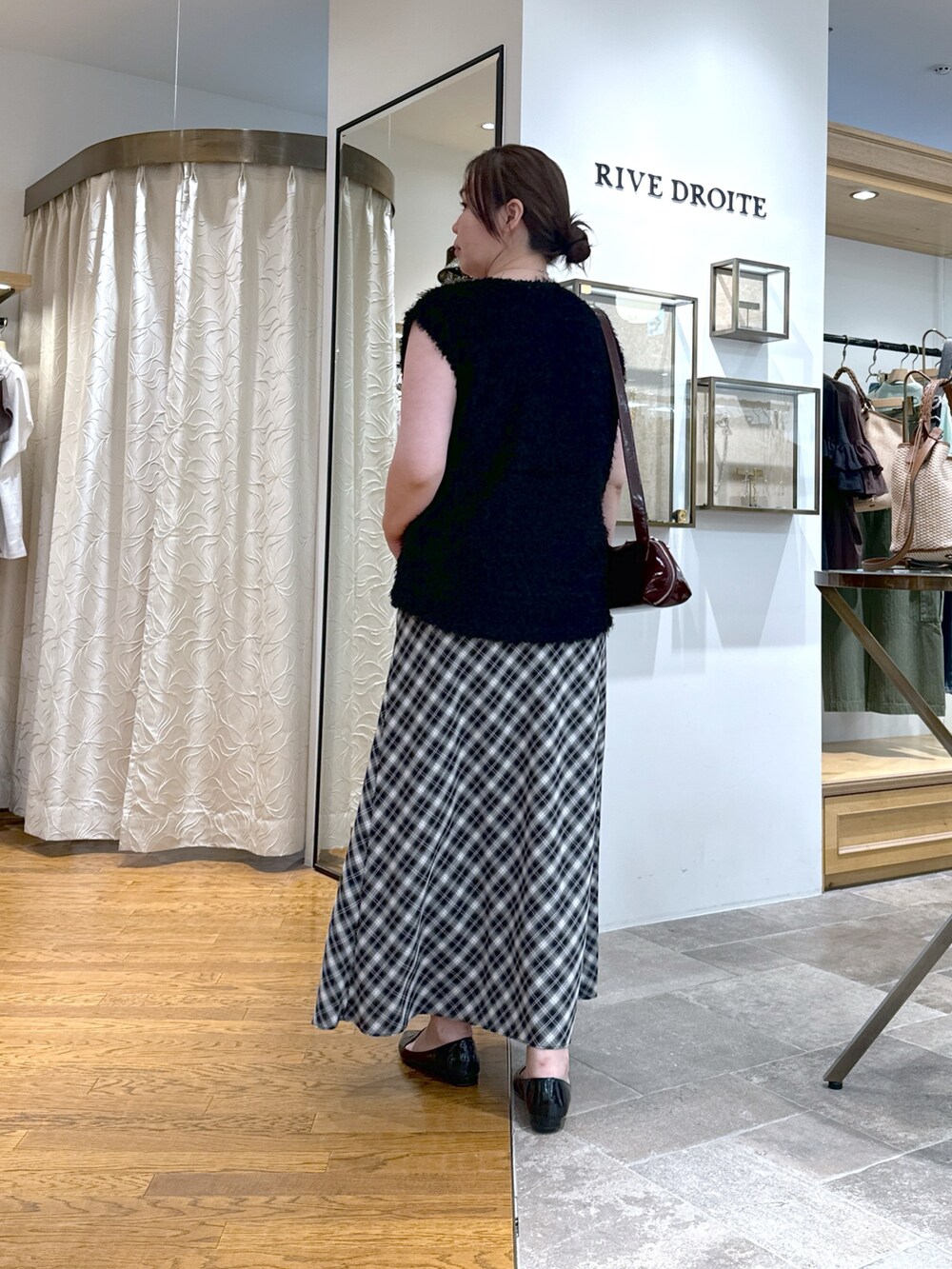 ブラック系のベスト、グレー系のタンクトップ、ブラック系のスカートを着用したレディースの夏コーディネートの4枚目の写真