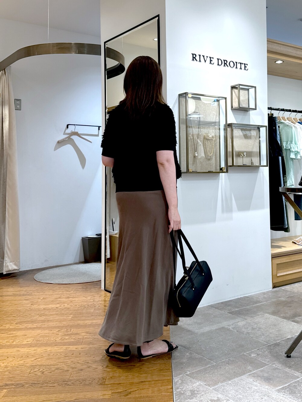 ブラウン系のスカート、ブラック系のショルダーバッグ、ブラック系のサンダルを着用したレディースの夏コーディネートの3枚目の写真