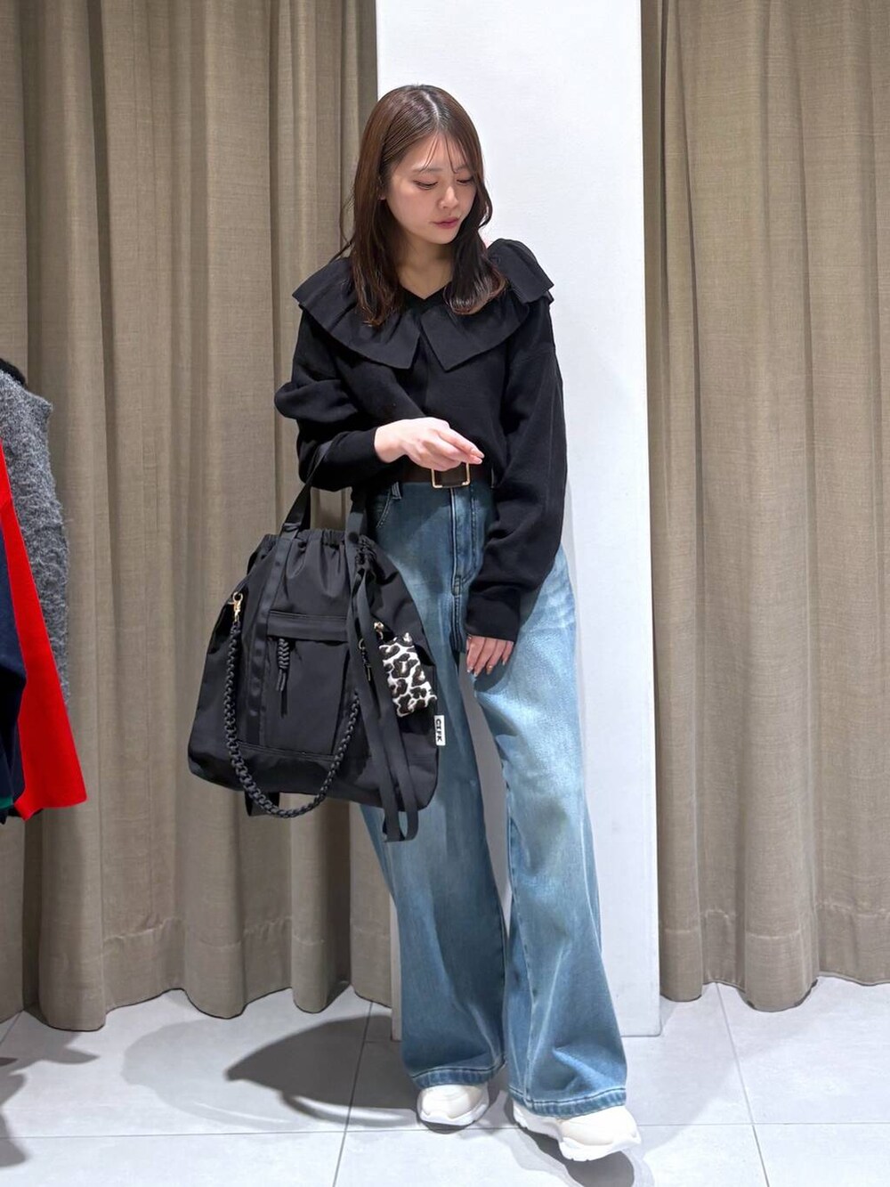 ブルー系のデニムパンツ、ブラック系のニット/セーター、ホワイト系のスニーカーを着用したレディースの冬コーディネートの2枚目の写真