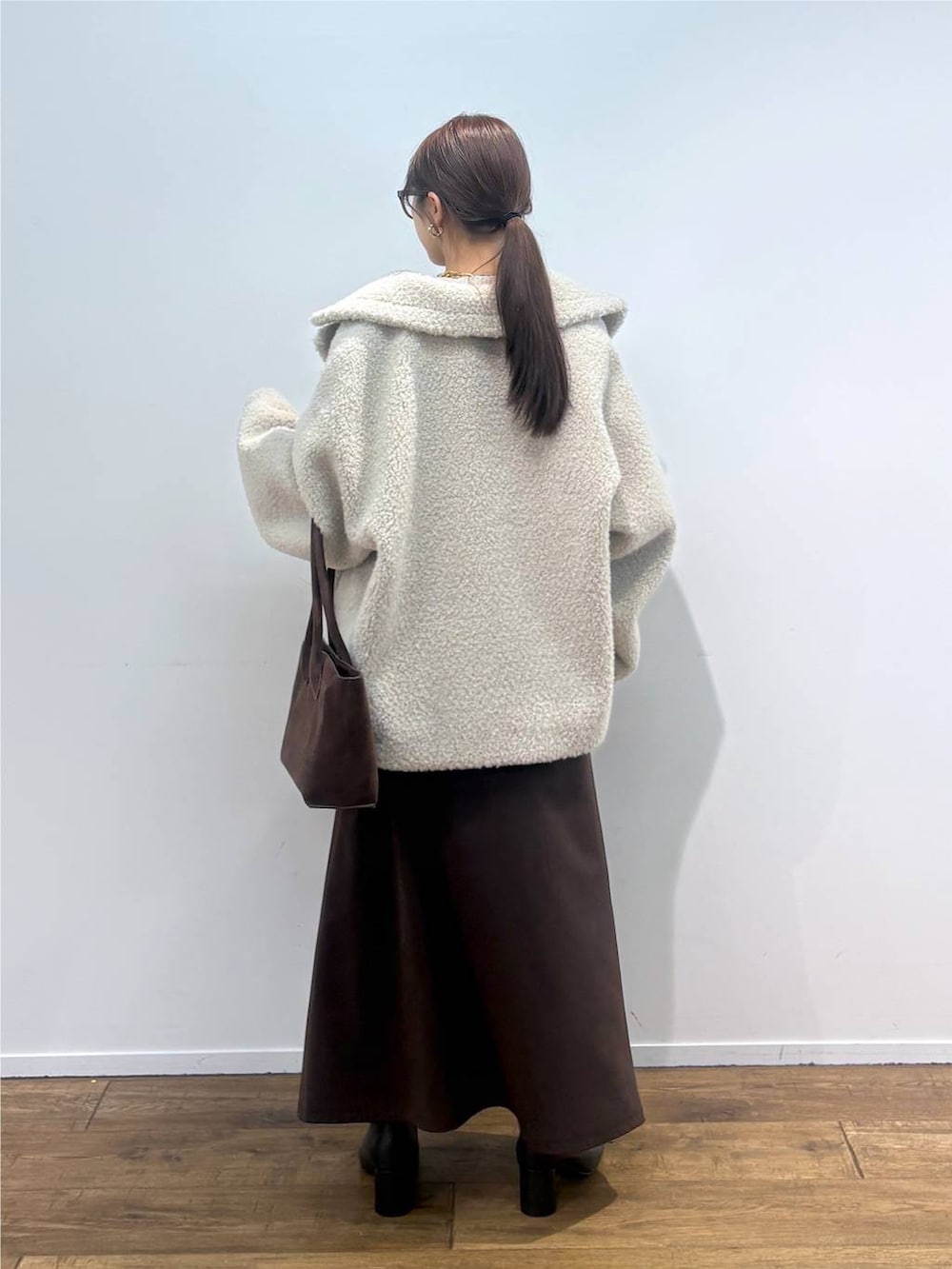 ホワイト系のニット/セーター、ホワイト系のピーコート、ゴールド系のネックレスを着用したレディースの夏コーディネートの3枚目の写真