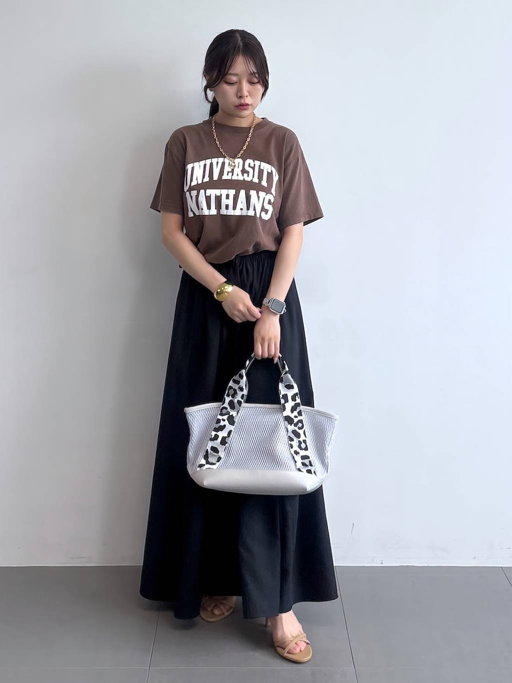 グレー系のトートバッグ、ベージュ系のサンダル、ブラック系のスカートを着用したレディースの夏コーディネートの6枚目の写真