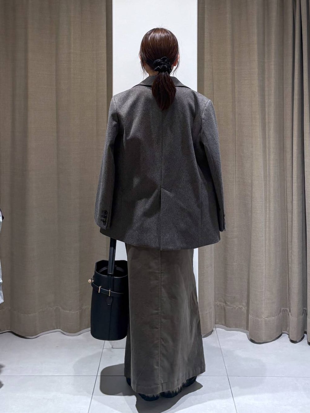 ブラウン系のテーラードジャケット、グレー系のニット/セーター、ブラウン系のスカートを着用したレディースの秋コーディネートの4枚目の写真