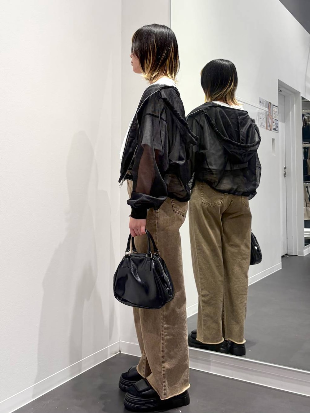 ブラック系のショルダーバッグ、ブラック系のサンダル、ベージュ系のデニムパンツを着用したレディースの春コーディネートの2枚目の写真