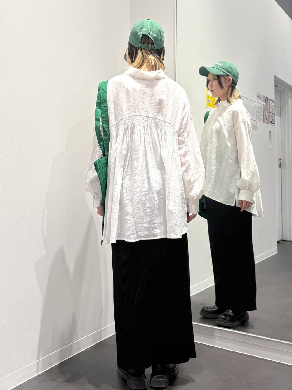 グリーン系のトートバッグ、ブラック系のスカート、ホワイト系のその他トップスを着用したレディースの春コーディネートの3枚目の写真