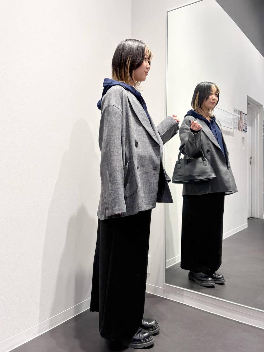 ブラック系のスカート、ブラック系のハンドバッグ、ブルー系のカーディガン/ボレロを着用したレディースの春コーディネートの4枚目の写真