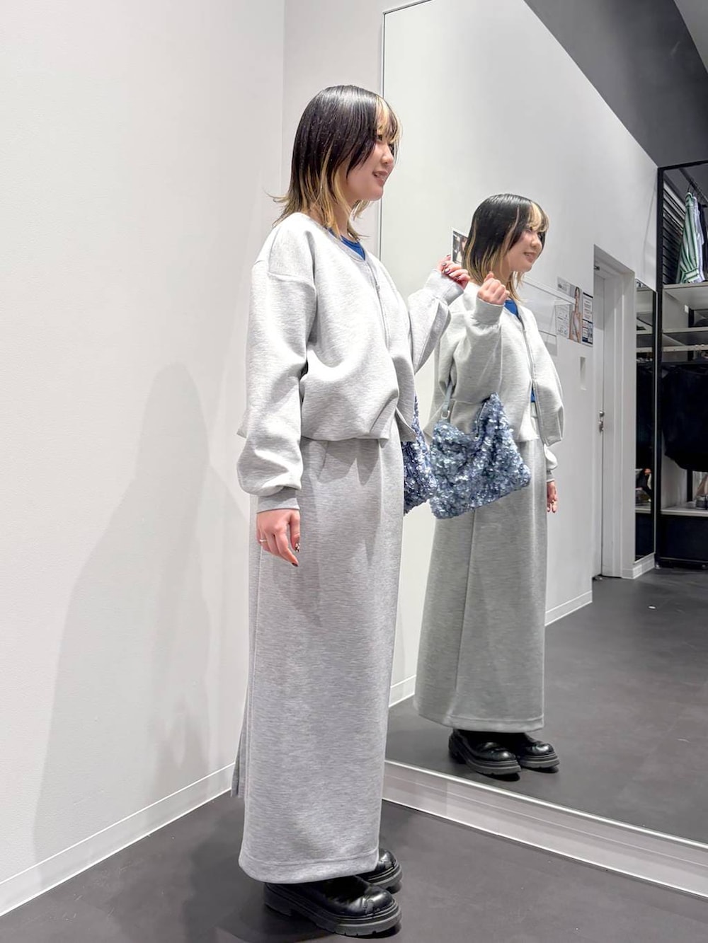 グレー系のスカート、グレー系のスウェット、ブルー系のショルダーバッグを着用したレディースの春コーディネートの4枚目の写真