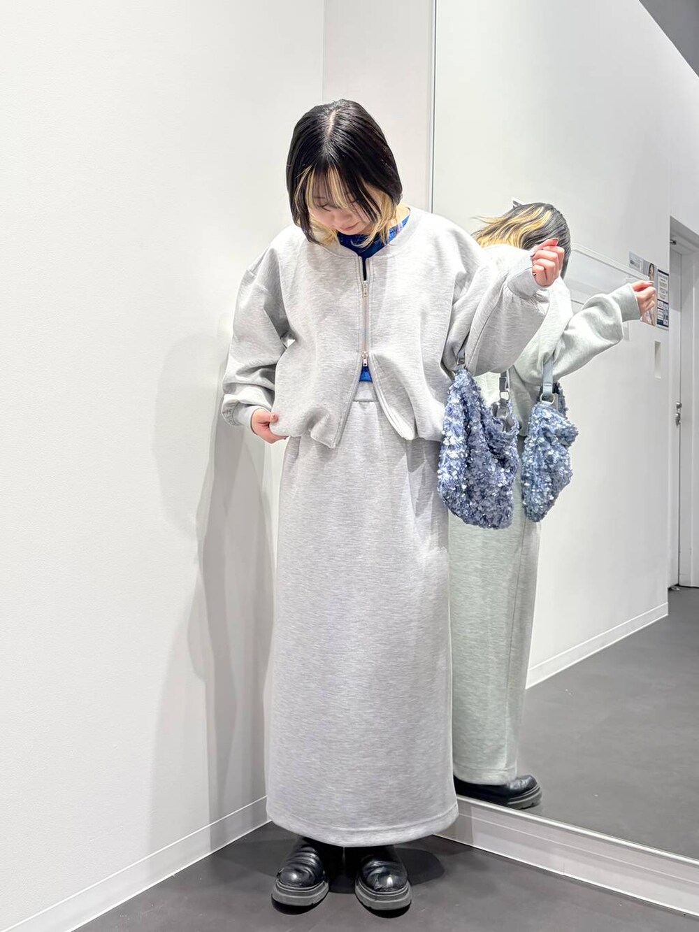 グレー系のスカート、グレー系のスウェット、ブルー系のショルダーバッグを着用したレディースの春コーディネートの5枚目の写真