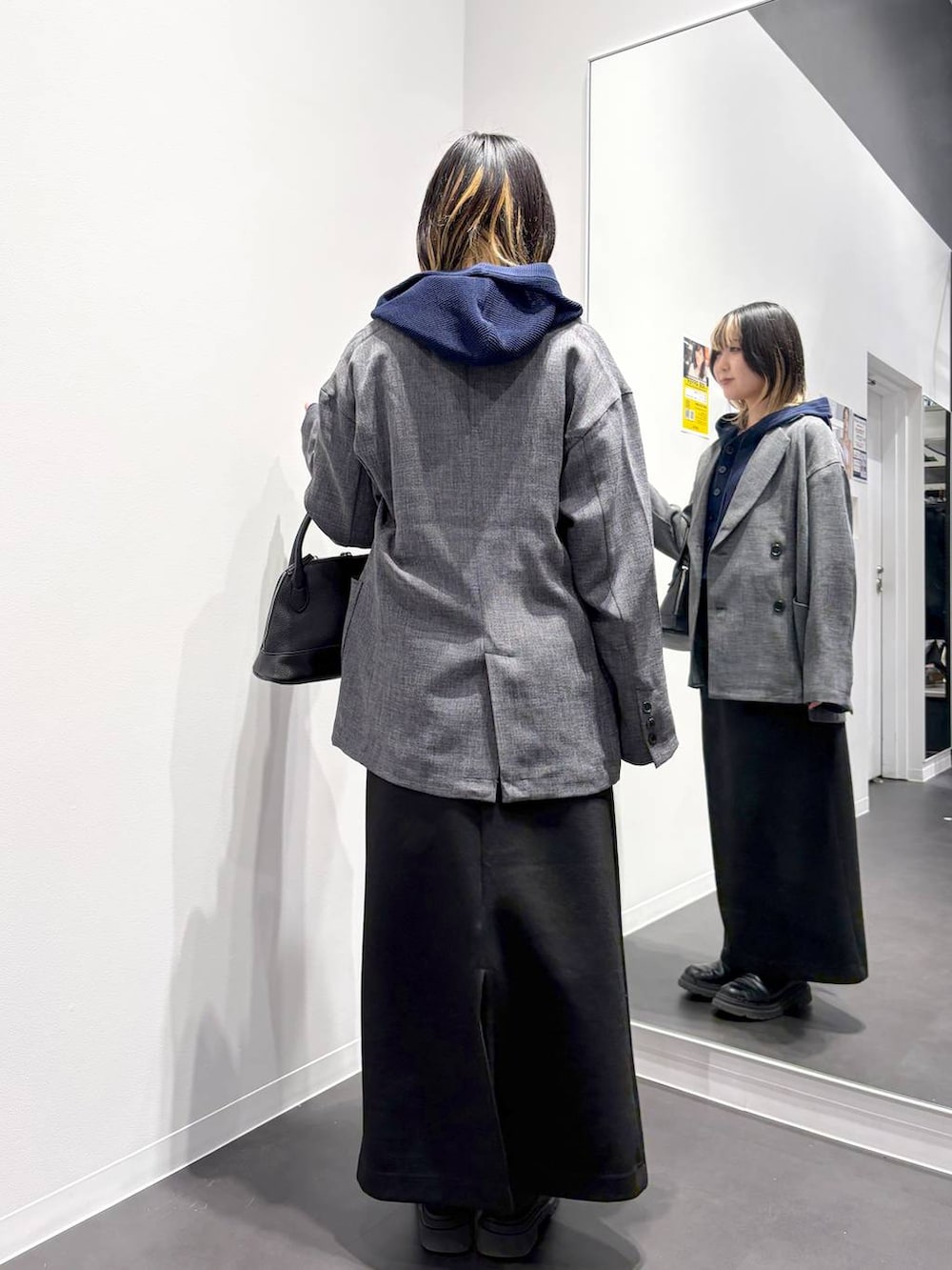 ブラック系のスカート、ブラック系のハンドバッグ、ブルー系のカーディガン/ボレロを着用したレディースの春コーディネートの3枚目の写真