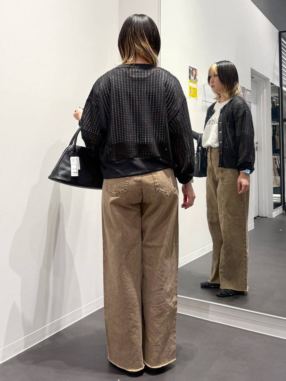 ブラック系のサンダル、ブラック系のハンドバッグ、ベージュ系のデニムパンツを着用したレディースの春コーディネートの3枚目の写真
