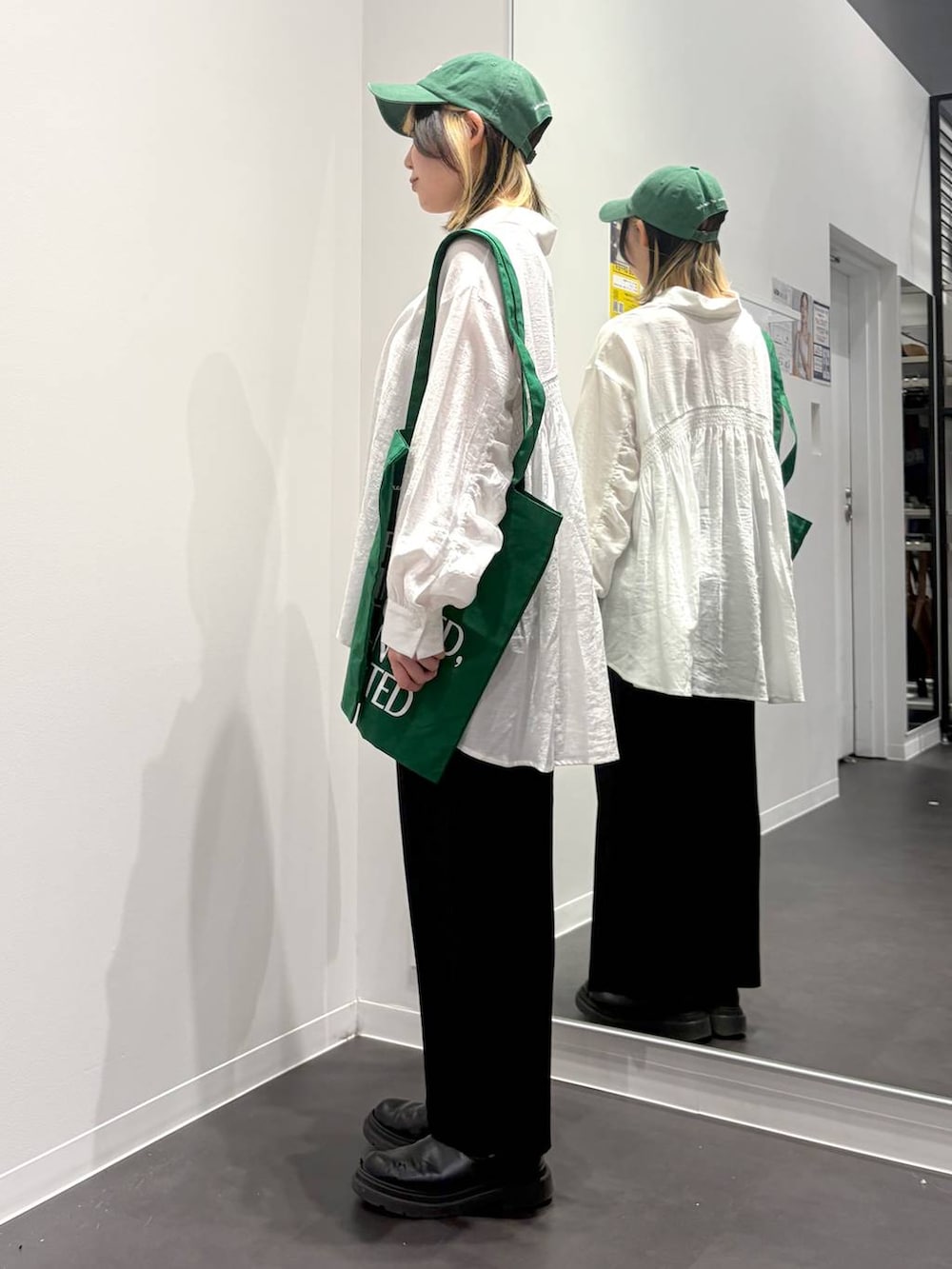 グリーン系のトートバッグ、ブラック系のスカート、ホワイト系のその他トップスを着用したレディースの春コーディネートの2枚目の写真