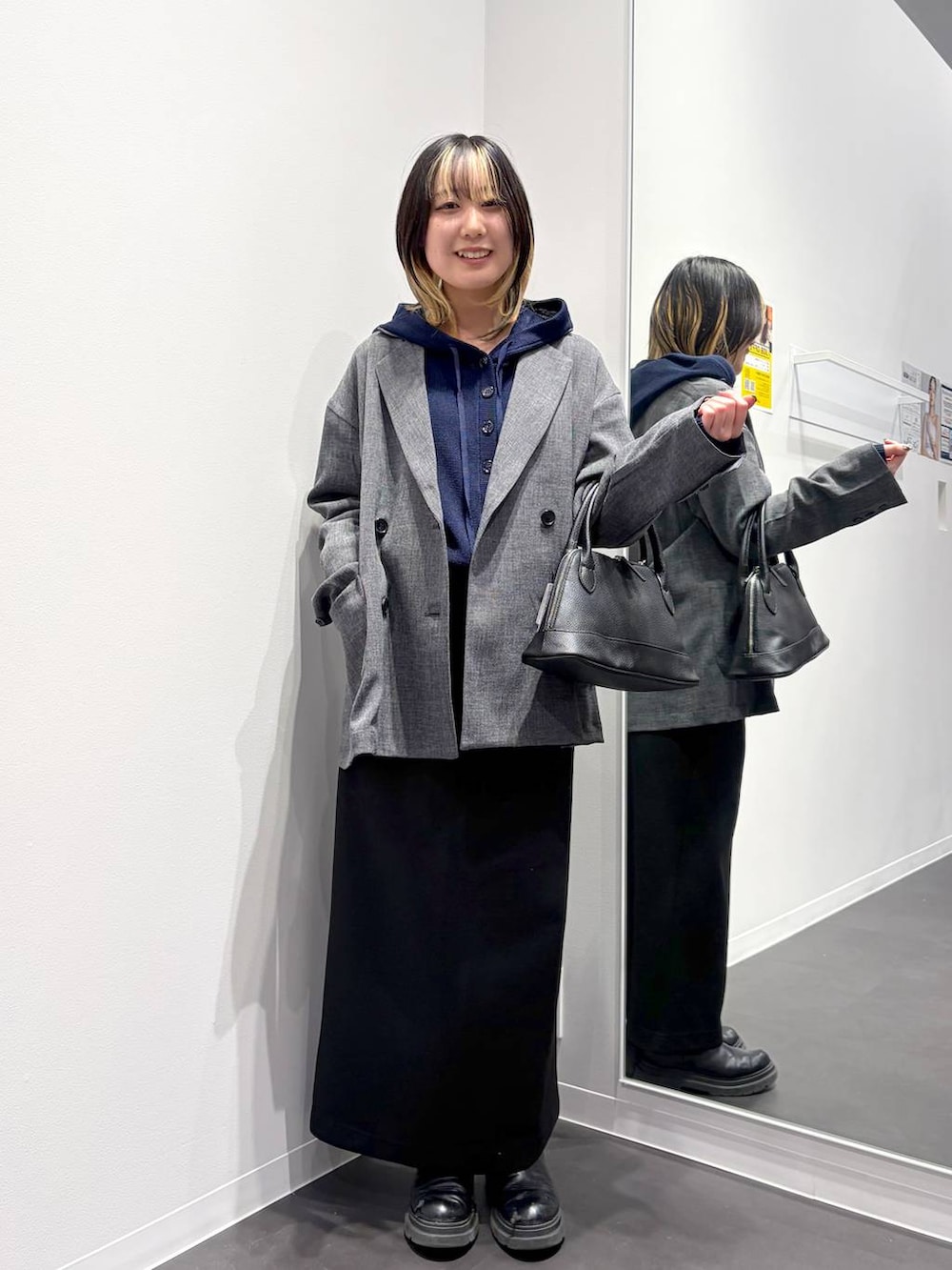 ブラック系のスカート、ブラック系のハンドバッグ、ブルー系のカーディガン/ボレロを着用したレディースの春コーディネートの5枚目の写真