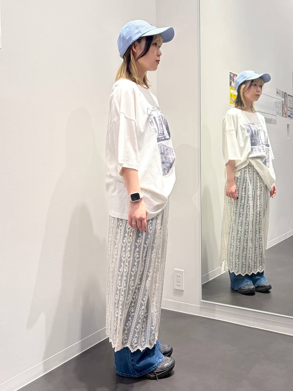 ブルー系のデニムパンツ、ホワイト系のTシャツ/カットソー、ベージュ系のスカートを着用したレディースの春コーディネートの4枚目の写真