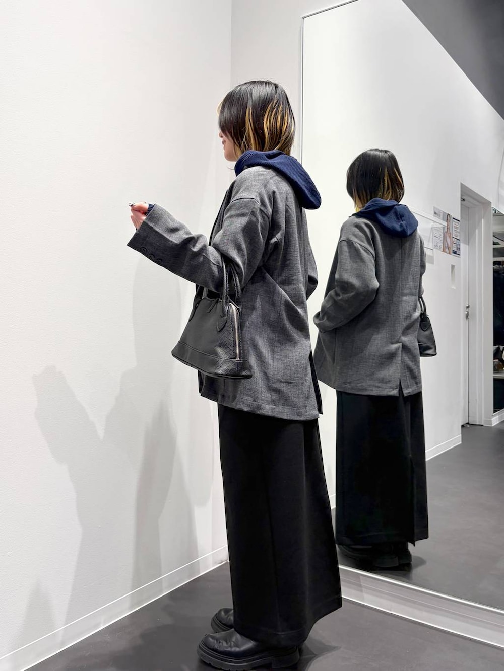 ブラック系のスカート、ブラック系のハンドバッグ、ブルー系のカーディガン/ボレロを着用したレディースの春コーディネートの2枚目の写真