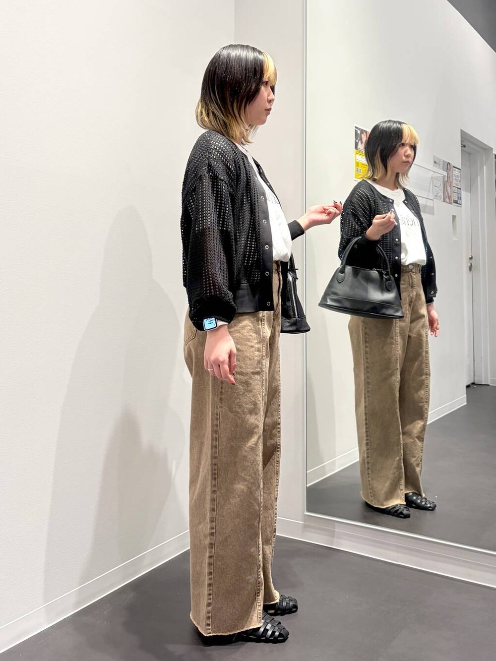 ブラック系のサンダル、ブラック系のハンドバッグ、ベージュ系のデニムパンツを着用したレディースの春コーディネートの4枚目の写真