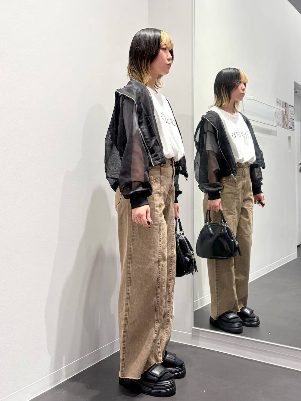 ブラック系のショルダーバッグ、ブラック系のサンダル、ベージュ系のデニムパンツを着用したレディースの春コーディネートの4枚目の写真