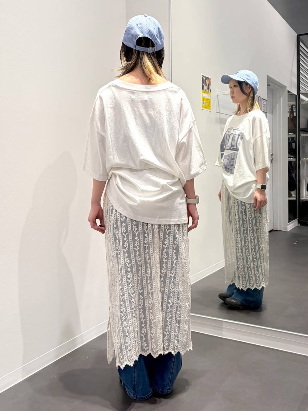 ブルー系のデニムパンツ、ホワイト系のTシャツ/カットソー、ベージュ系のスカートを着用したレディースの春コーディネートの3枚目の写真