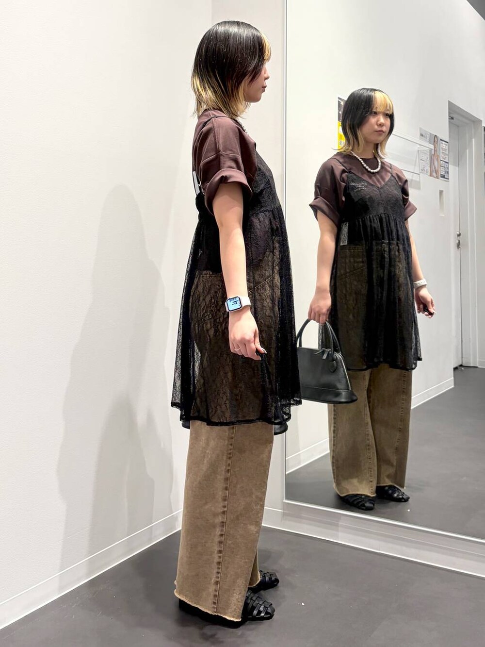ブラック系のサンダル、ブラック系のハンドバッグ、ベージュ系のデニムパンツを着用したレディースの春コーディネートの4枚目の写真