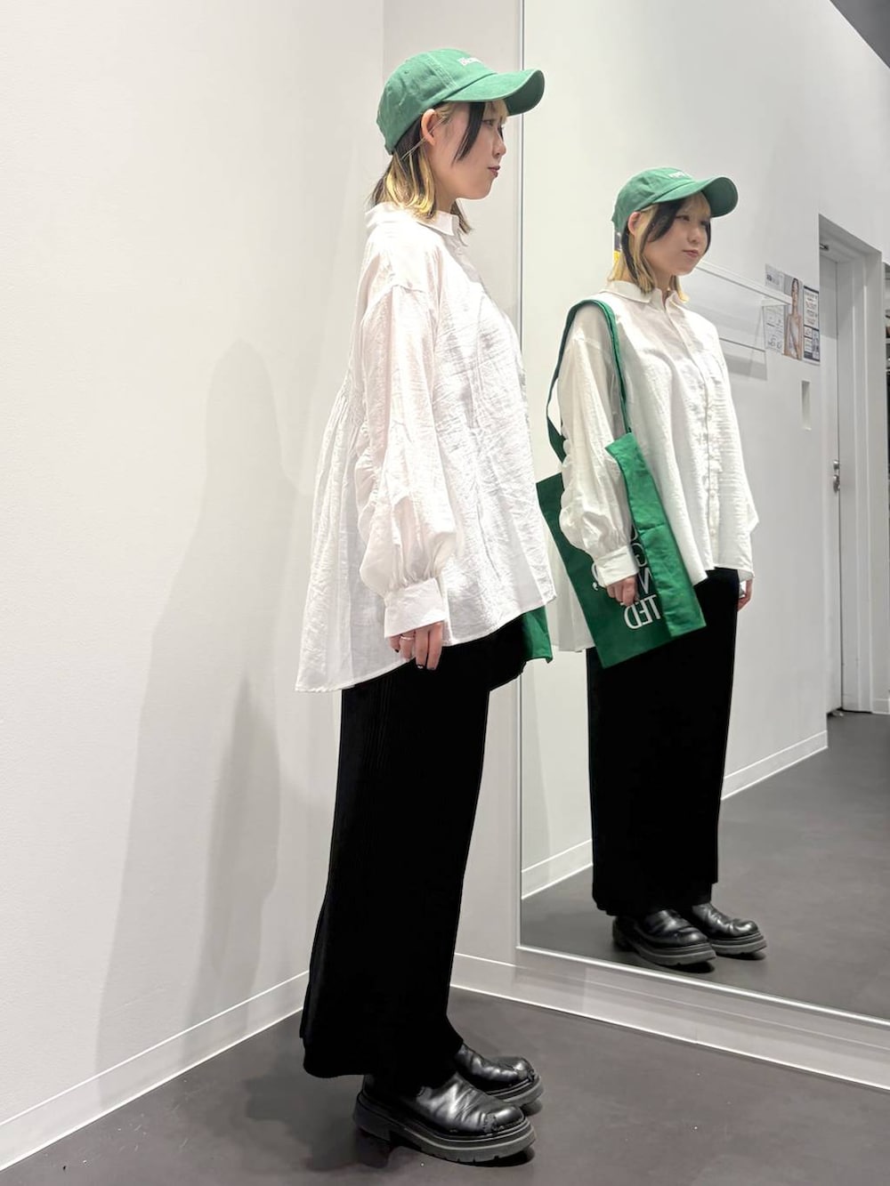 グリーン系のトートバッグ、ブラック系のスカート、ホワイト系のその他トップスを着用したレディースの春コーディネートの4枚目の写真