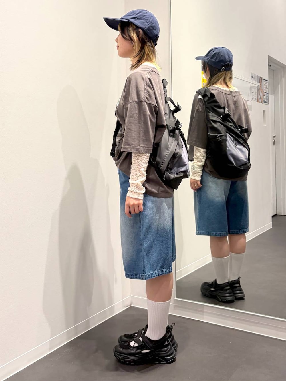 ブラック系のスニーカー、ブラック系のボディバッグ/ウエストポーチ、ホワイト系のTシャツ/カットソーを着用したレディースの春コーディネートの2枚目の写真