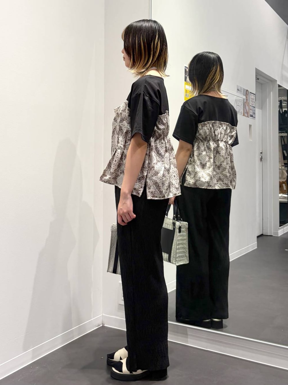 ホワイト系のショルダーバッグ、ホワイト系のサンダル、ブラック系のTシャツ/カットソーを着用したレディースの春コーディネートの2枚目の写真