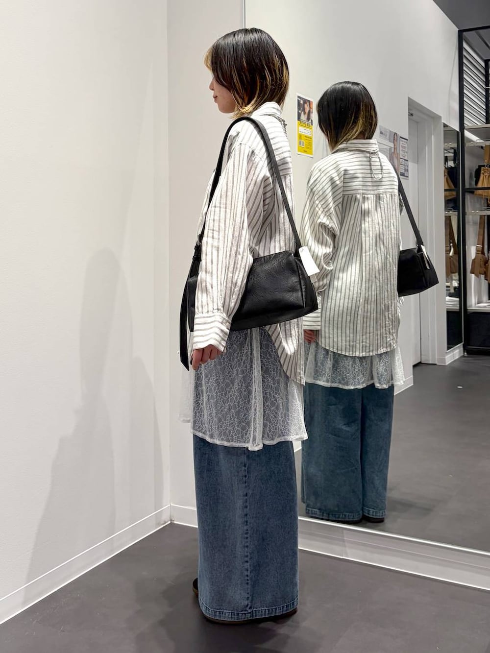 ブラック系のショルダーバッグ、ホワイト系のシャツ/ブラウス、ブルー系のデニムパンツを着用したレディースの春コーディネートの2枚目の写真