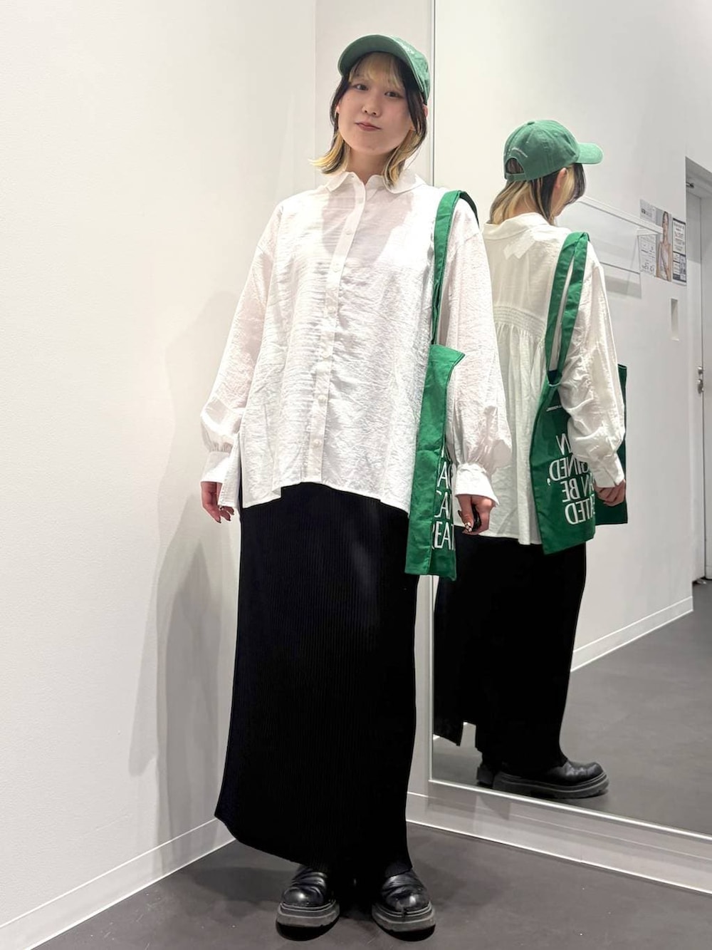 グリーン系のトートバッグ、ブラック系のスカート、ホワイト系のその他トップスを着用したレディースの春コーディネートの5枚目の写真