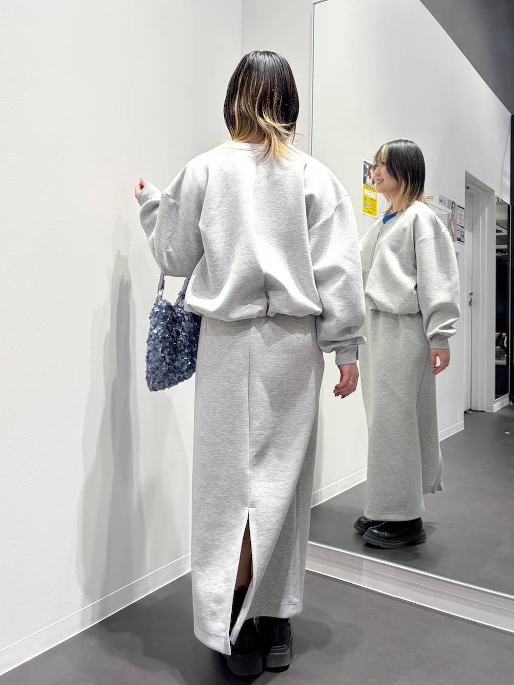 グレー系のスカート、グレー系のスウェット、ブルー系のショルダーバッグを着用したレディースの春コーディネートの3枚目の写真