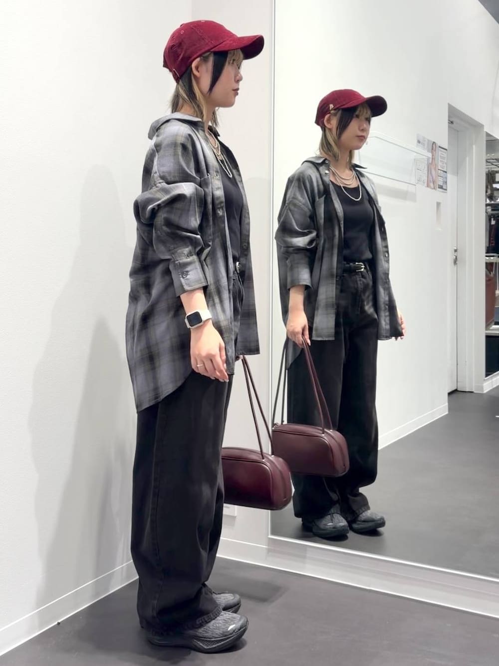 グレー系のシャツ/ブラウス、レッド系のボストンバッグ、ブラック系のデニムパンツを着用したレディースの秋コーディネートの4枚目の写真