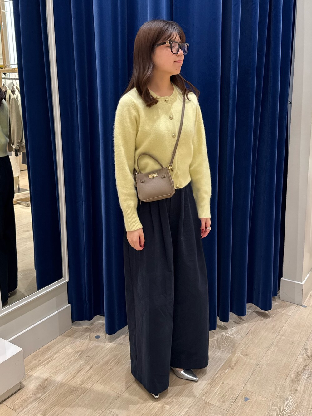 イエロー系のカーディガン/ボレロ、ブルー系のその他パンツ、ベージュ系のショルダーバッグを着用したレディースの秋コーディネートの3枚目の写真