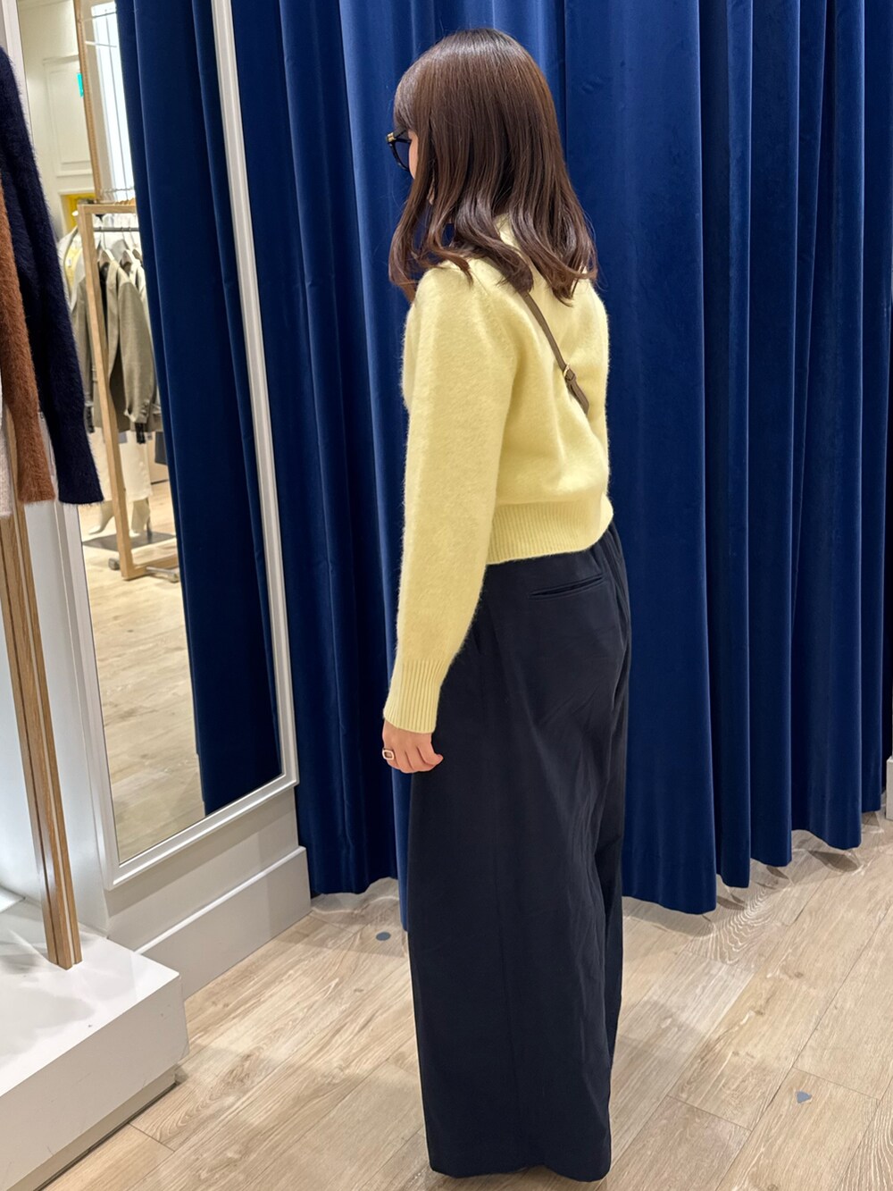 イエロー系のカーディガン/ボレロ、ブルー系のその他パンツ、ベージュ系のショルダーバッグを着用したレディースの秋コーディネートの2枚目の写真