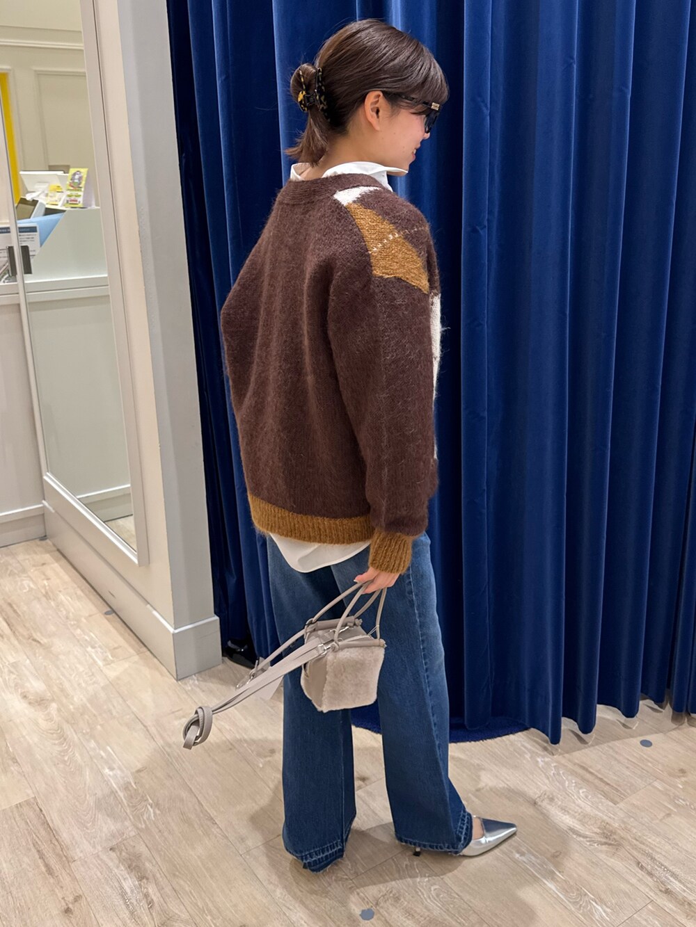 ブラウン系のカーディガン/ボレロ、ホワイト系のシャツ/ブラウス、ブルー系のデニムパンツを着用したレディースの秋コーディネートの3枚目の写真