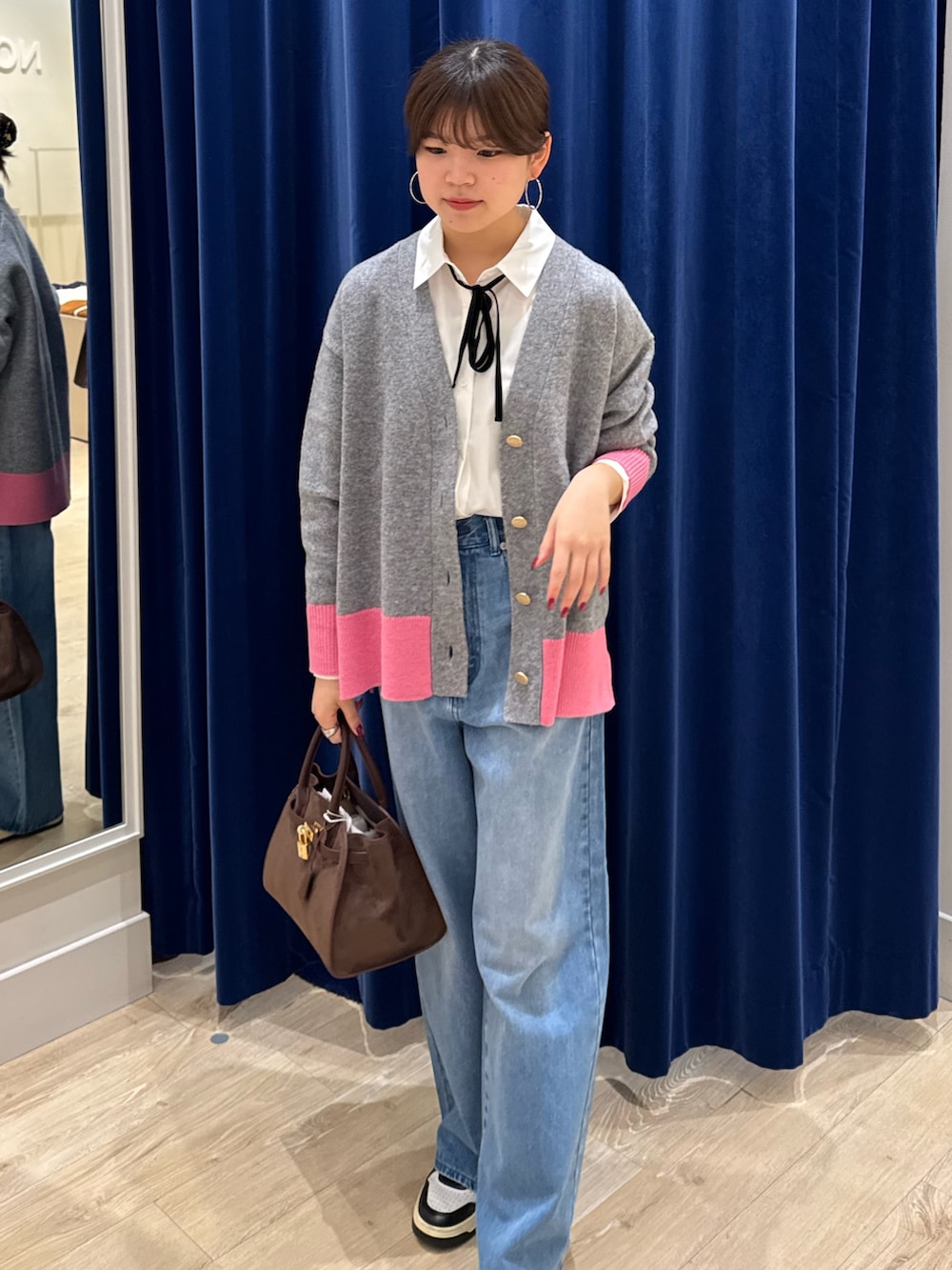 グレー系のカーディガン/ボレロ、ホワイト系のシャツ/ブラウス、ブルー系のデニムパンツを着用したレディースの秋コーディネートの2枚目の写真