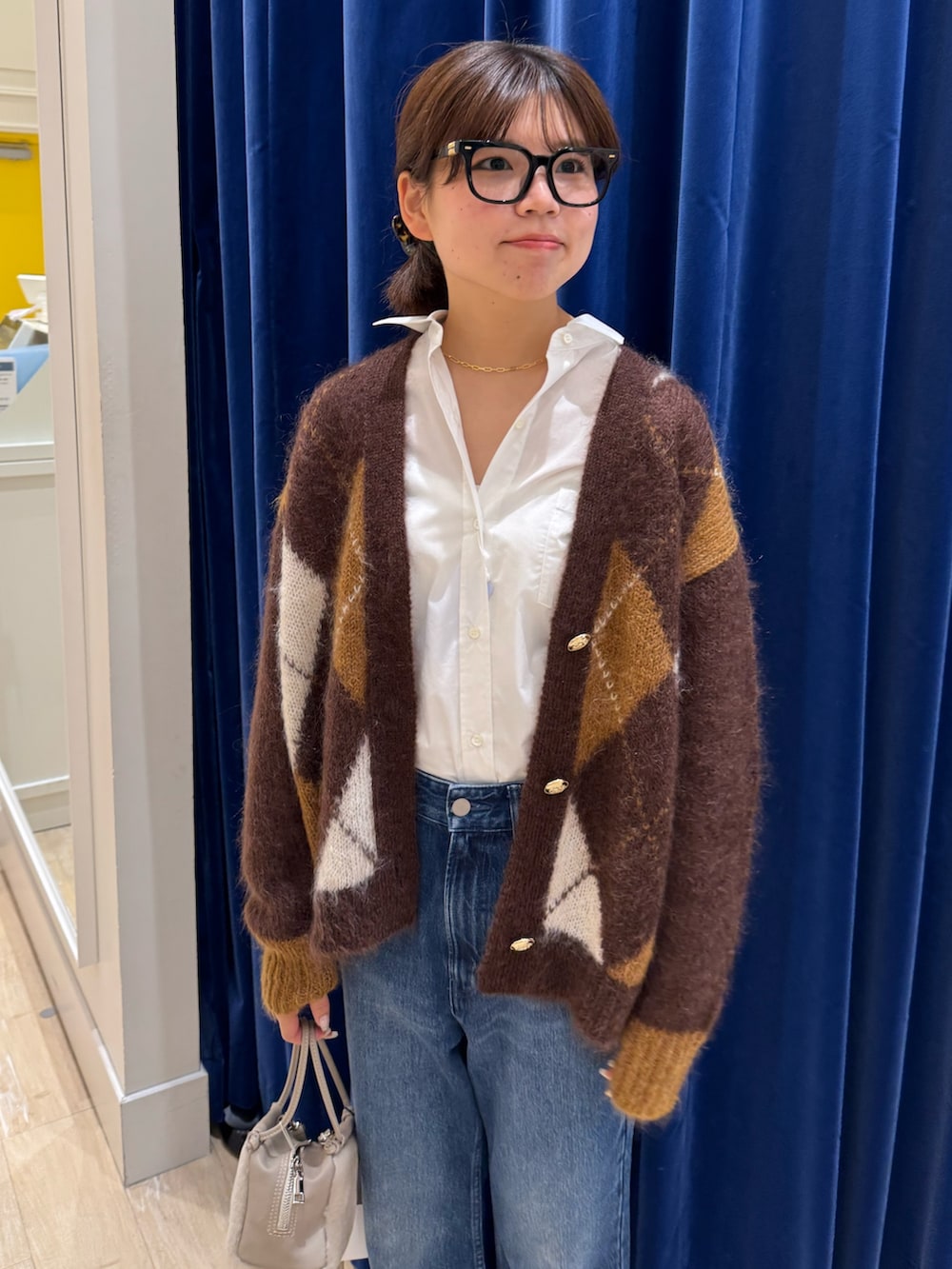 ブラウン系のカーディガン/ボレロ、ホワイト系のシャツ/ブラウス、ブルー系のデニムパンツを着用したレディースの秋コーディネートの4枚目の写真