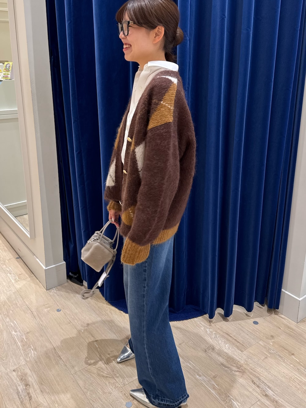 ブラウン系のカーディガン/ボレロ、ホワイト系のシャツ/ブラウス、ブルー系のデニムパンツを着用したレディースの秋コーディネートの2枚目の写真