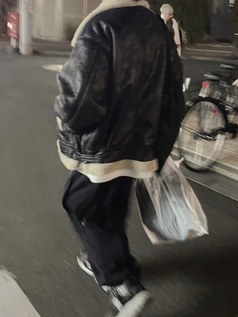 ブラック系のムートンコート、グレー系のTシャツ/カットソー、ブルー系のパンツを着用したメンズの冬コーディネートの2枚目の写真